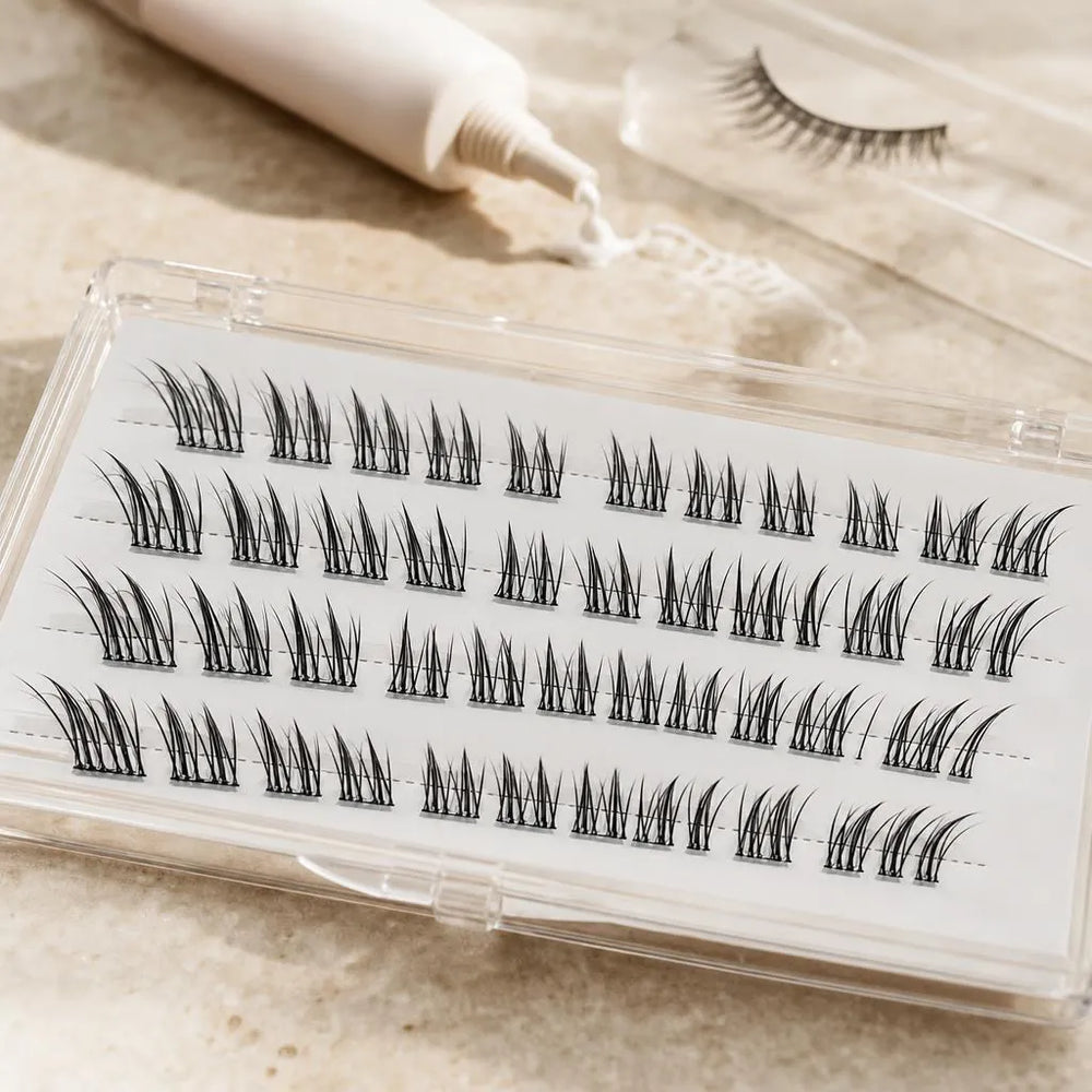 Lash cluster case in front of a tube of lash glue and strip lashes