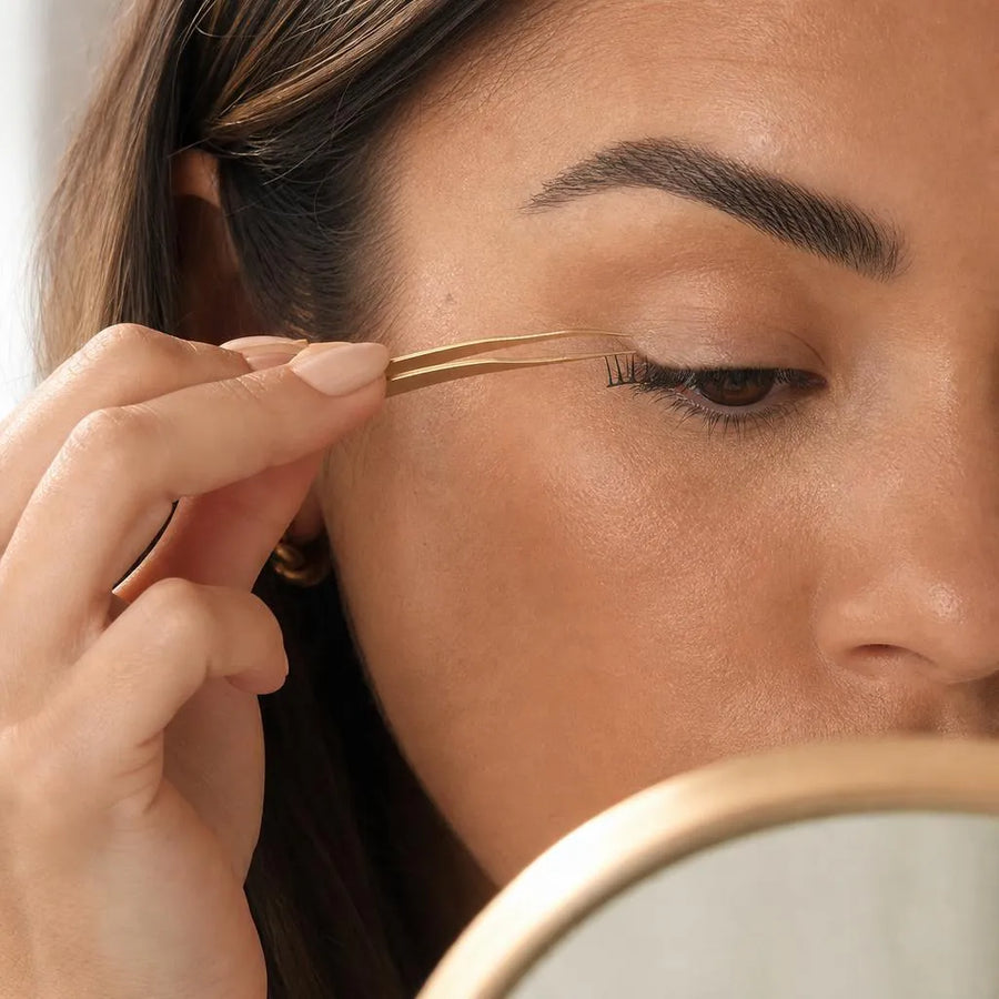 Placing a pre-glued lash cluster under the natural lashes with tweezers